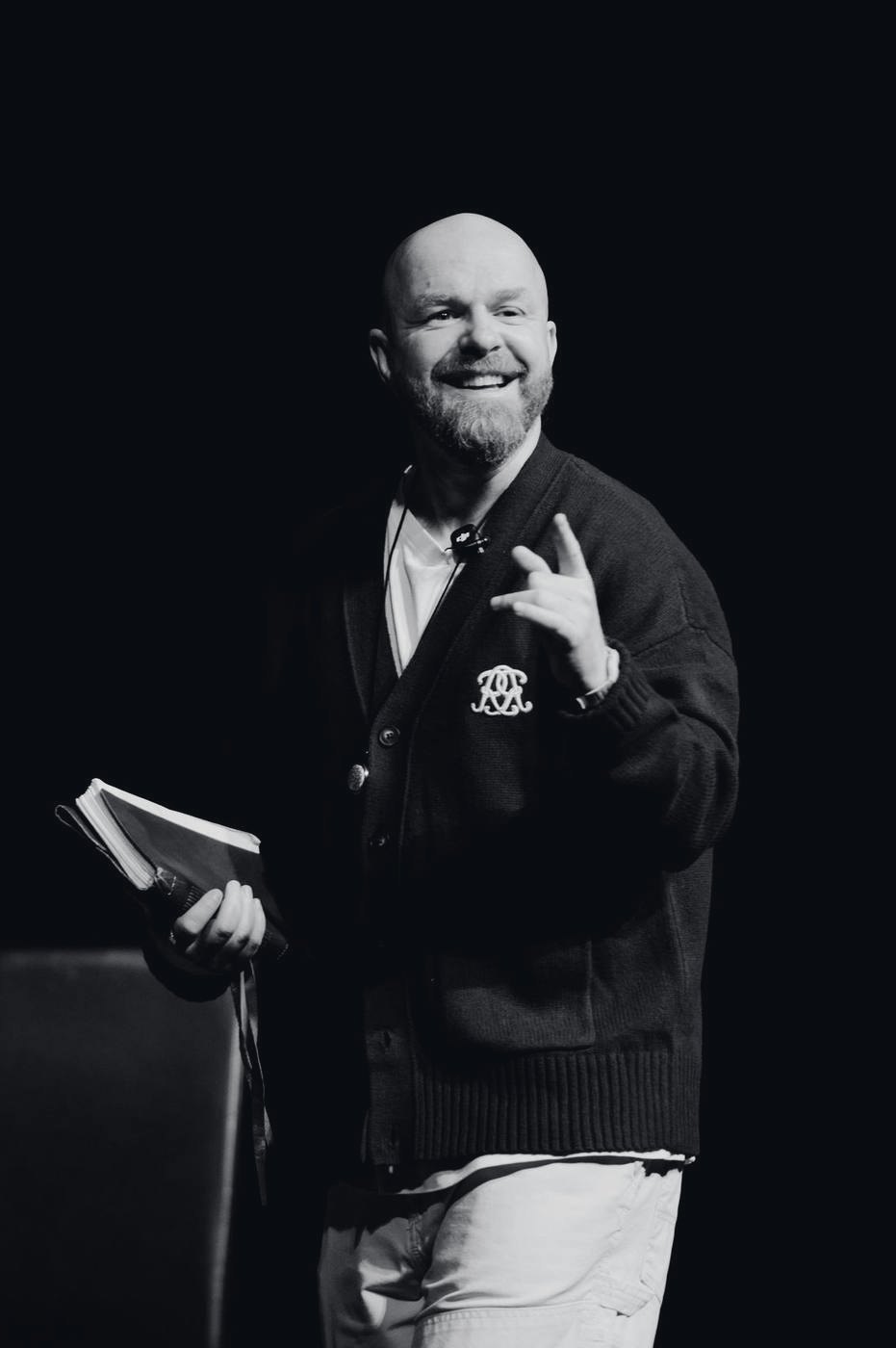 Luke Staton on stage, smiling, a copy of Credo in his hand.